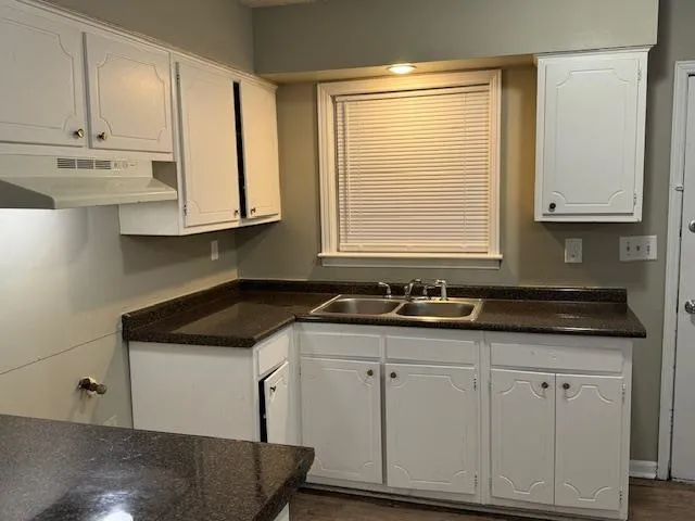 a kitchen with granite countertop white cabinets and a sink