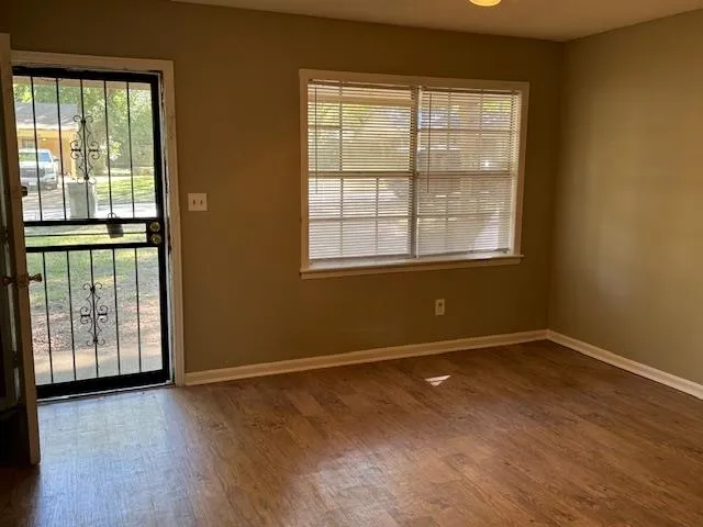 an empty room with wooden floor and windows