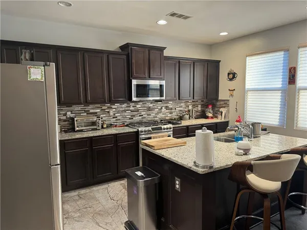 a kitchen with a stove a refrigerator and a dining table with wooden floor