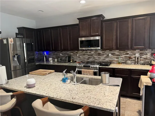 a kitchen with kitchen island granite countertop wooden cabinets a stove and a sink
