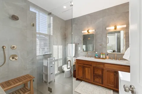 a spacious bathroom with a double vanity sink toilet mirror and shower