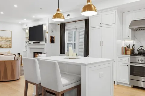 a living room with stainless steel appliances white cabinets a table and chairs