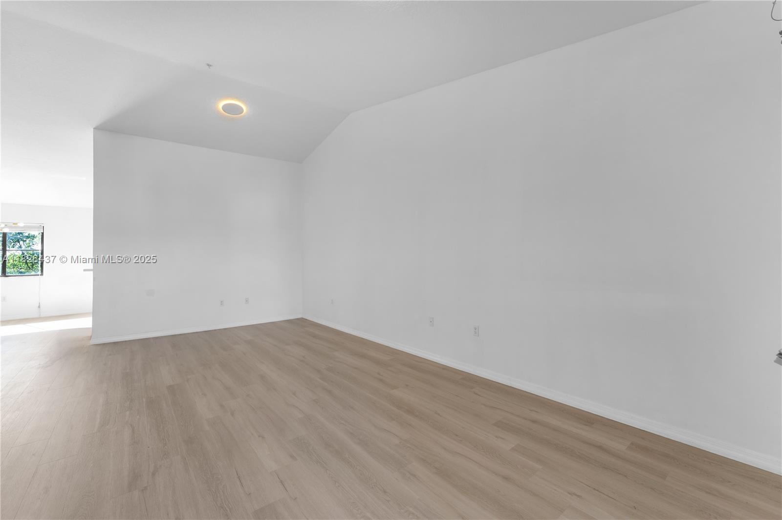 22921 Southwest 88th Place, Unit 301 Cutler Bay, FL 33190 - Photo 4 of 24 a view of an empty room with wooden floor and a window