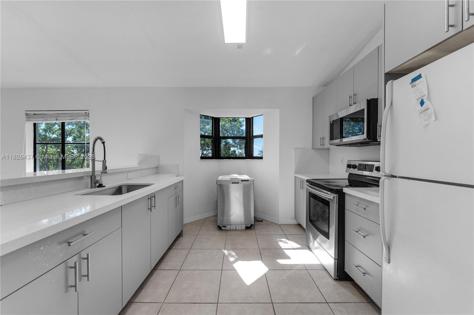 22921 Southwest 88th Place, Unit 301 Cutler Bay, FL 33190 - Photo 8 of 24 a kitchen with a sink stove and refrigerator