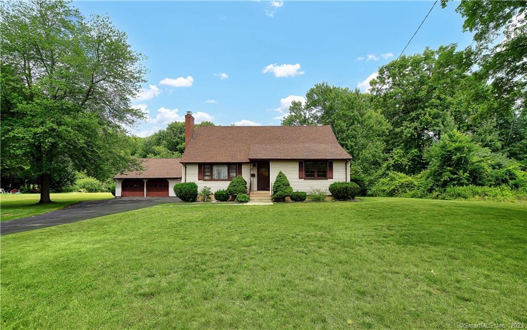 a view of a house with a big yard potted plants and large tree