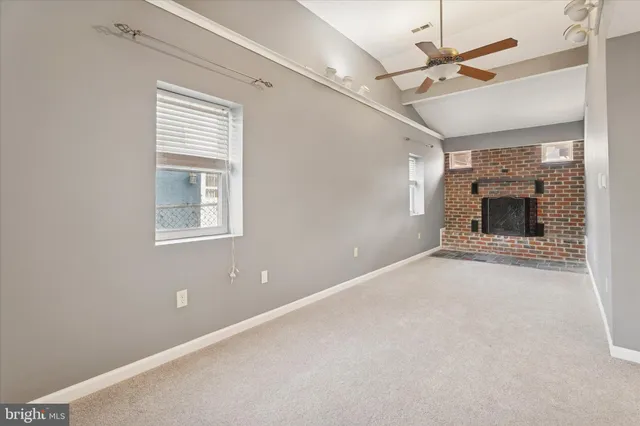 an empty room with windows and fireplace