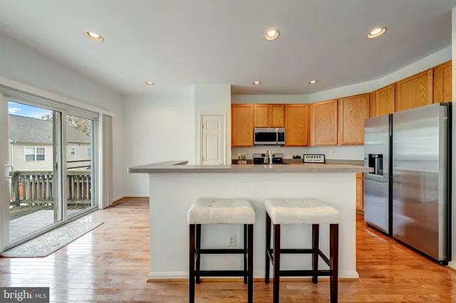 a kitchen with stainless steel appliances granite countertop a refrigerator a stove a sink and a microwave with wooden floor