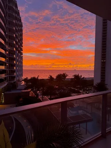 a view of a dining room and livingroom with furniture wooden floor a rug a fireplace and a chandelier
