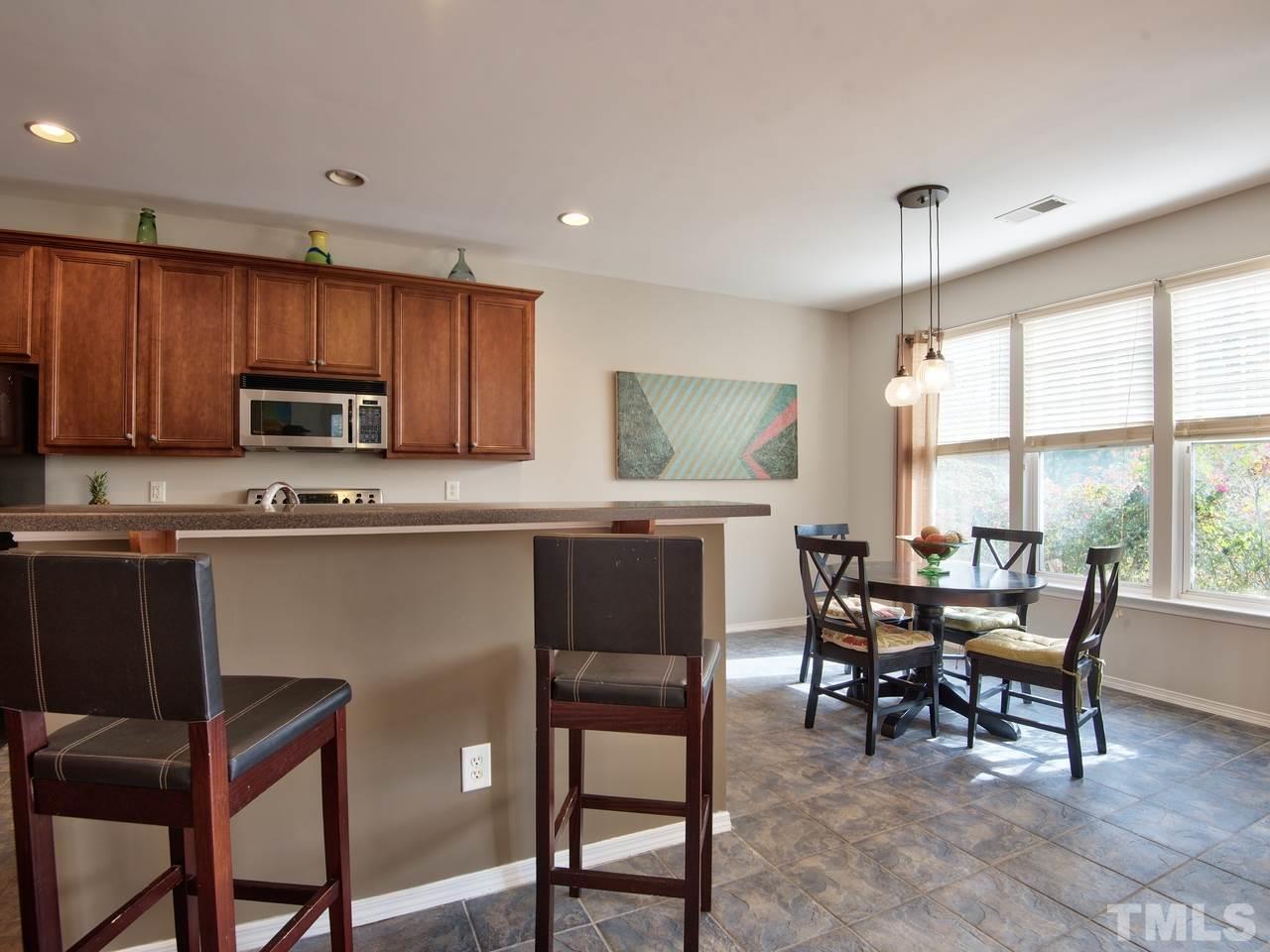 8415 Stonework Drive Raleigh, NC 27613 - Photo 12 of 24 a kitchen with granite countertop sink dining table and chairs