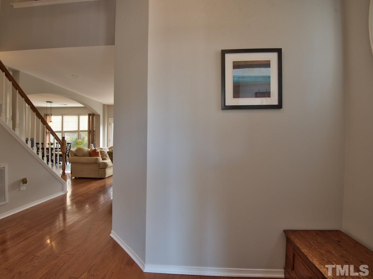 8415 Stonework Drive Raleigh, NC 27613 - Photo 4 of 24 a view of a hallway with couches and dinning room with wooden floor