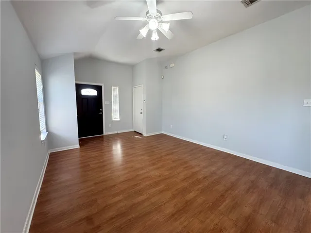 a view of an empty room with window and wooden floor