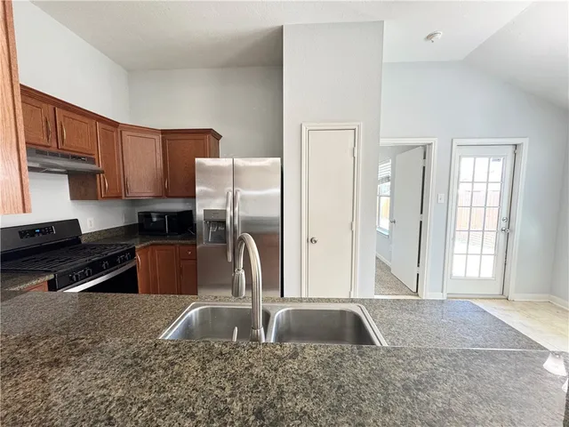 a kitchen with stainless steel appliances granite countertop a sink a stove and a refrigerator