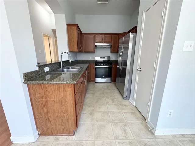 a kitchen with stainless steel appliances granite countertop a refrigerator a sink and a stove