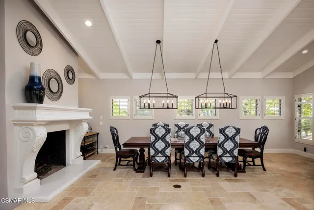 a kitchen with stainless steel appliances granite countertop a dining table chairs and a refrigerator
