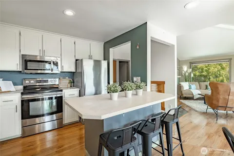 a kitchen with stainless steel appliances a dining table chairs stove refrigerator and microwave
