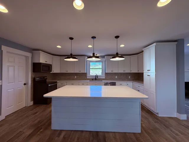 a large kitchen with stainless steel appliances a large counter top a stove and a wooden floors