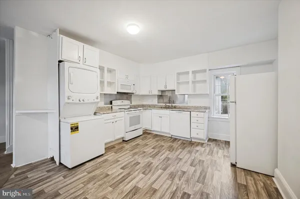 a kitchen with stainless steel appliances a refrigerator a sink and white cabinets