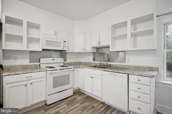 a kitchen with granite countertop white cabinets and white appliances