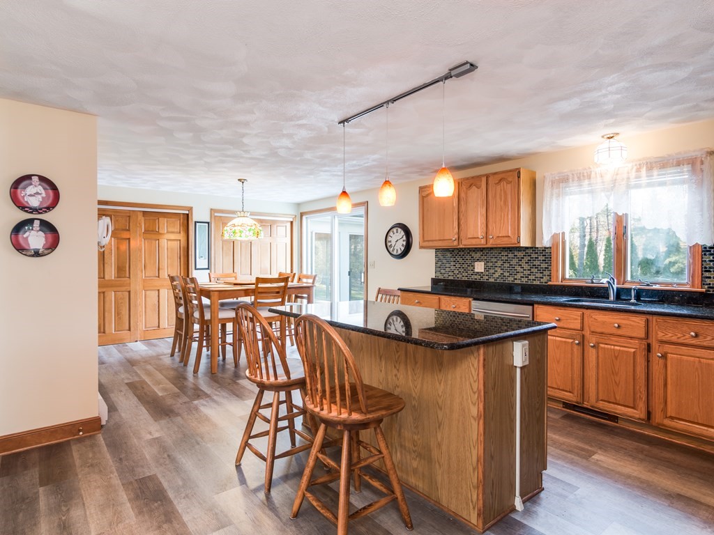 7 Old Town Road Beverly, MA 01915 - Photo 12 of 35 a kitchen with stainless steel appliances kitchen island granite countertop a table chairs in it and wooden floors