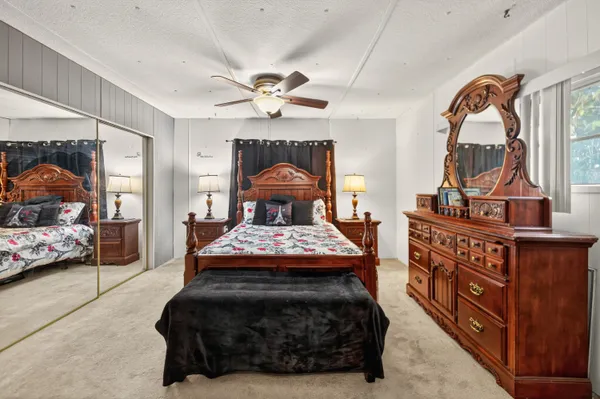 a bedroom with a bed a mirror on dresser and a chandelier