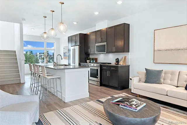a living room with stainless steel appliances furniture and a kitchen view