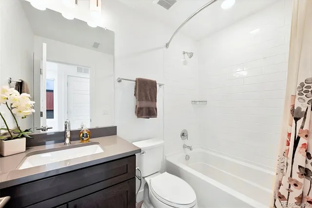 a bathroom with a granite countertop sink a toilet a mirror a bathtub and shower