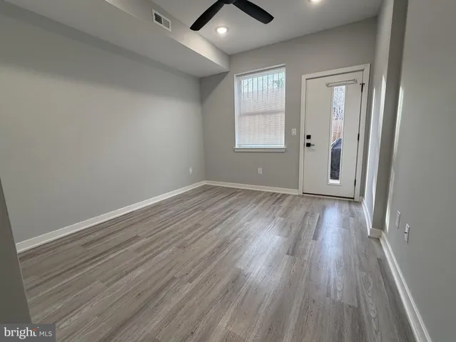 an empty room with wooden floor and a ceiling fan