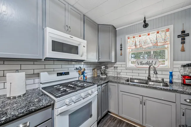 a kitchen with granite countertop cabinets stainless steel appliances a sink and a window