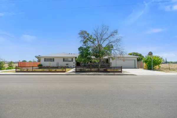 a front view of a house with a yard and a car parked on road