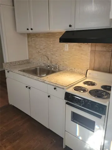 a kitchen with granite countertop white cabinets and a stove top oven