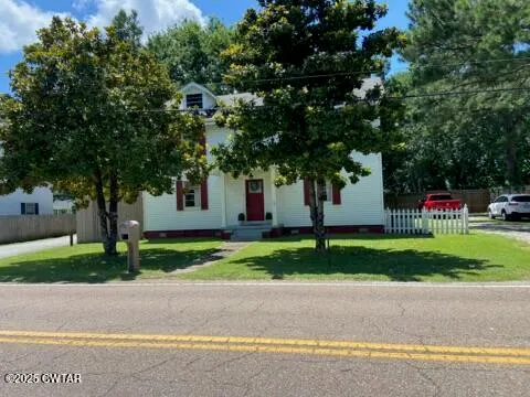 a front view of a house with a yard and trees