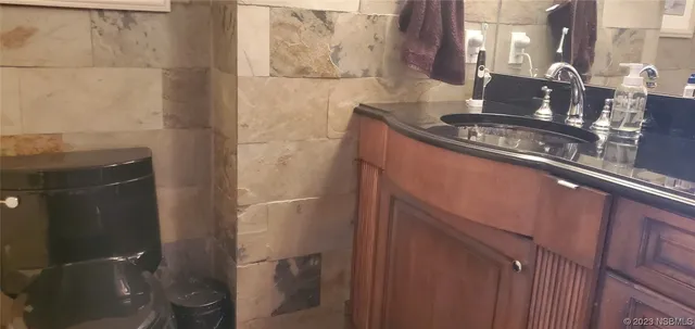 a bathroom with a granite countertop sink a toilet and a mirror