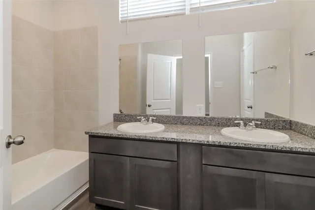 a bathroom with a granite countertop sink a mirror and a bathtub