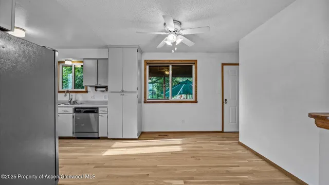 a view of a kitchen with a sink a ceiling fan and windows