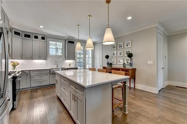 a kitchen with kitchen island granite countertop a stove a sink a center island and wooden floor