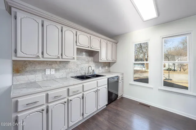 a kitchen with stainless steel appliances granite countertop a stove a sink and white cabinets