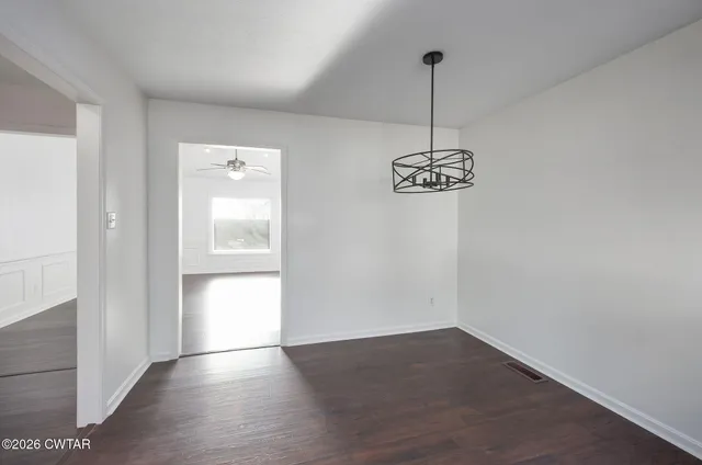 a view of a room with wooden floor chandelier and a window