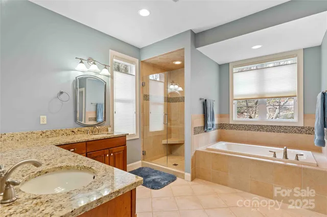 a bathroom with a granite countertop tub sink and mirror