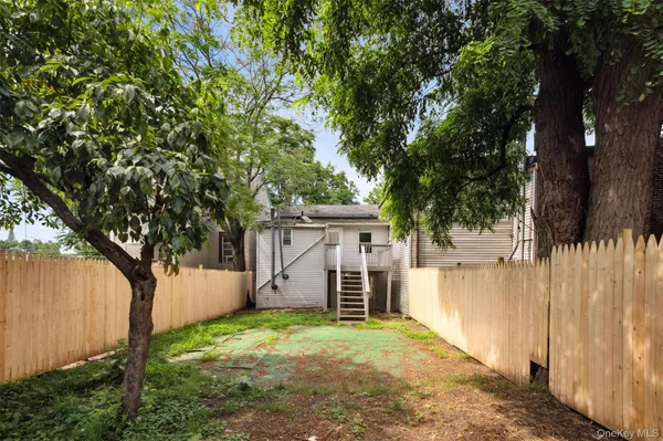 a backyard of a house with large trees and wooden fence