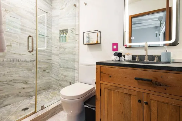 a bathroom with a toilet a sink a mirror and shower