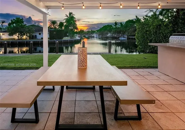 a view of a patio with table and chairs a barbeque with wooden floor and fence