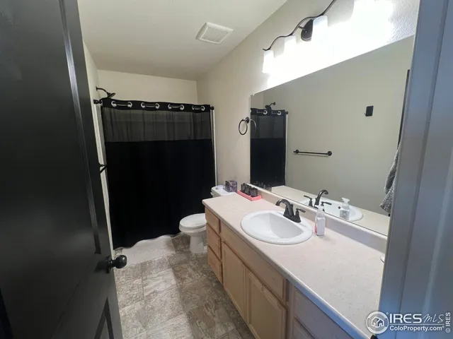 a bathroom with a sink a toilet a mirror and shower