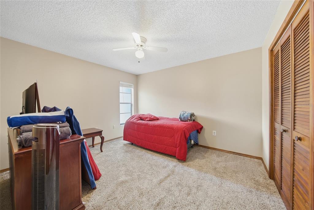 8398 Begonia Street Spring Hill, FL 34608 - Photo 11 of 32 a bedroom with a bed and a chandelier