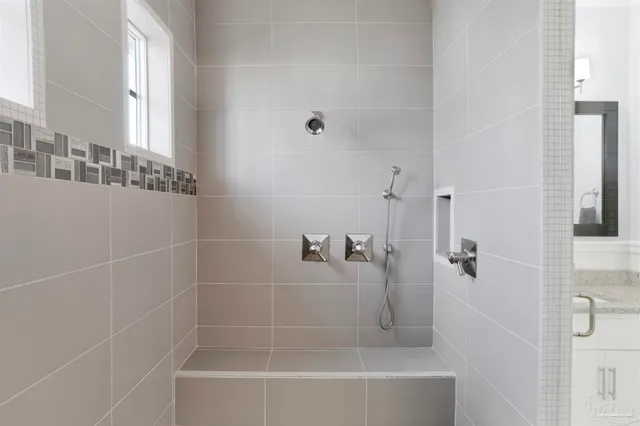 a bedroom with a bed a mirror on dresser and a flat screen tv