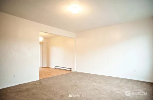 a view of an empty room with wooden floor and windows