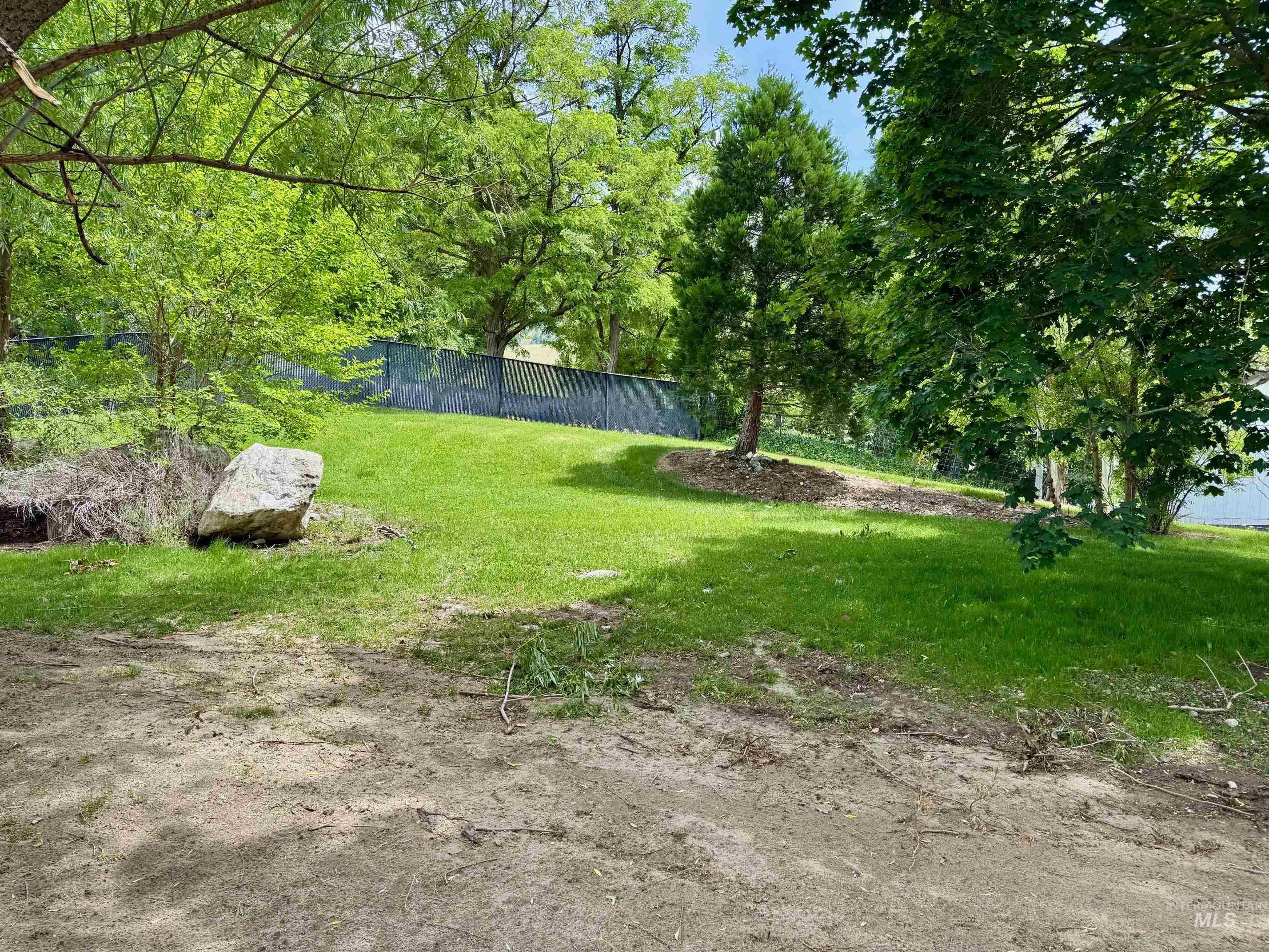 151 Cow Creek Road Lucile, ID 83542 - Photo 42 of 50 Expansive green lawn with mature trees and a chain-link fence