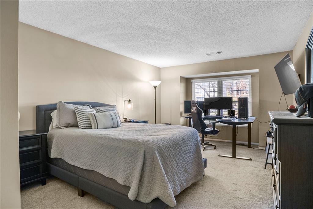 32 Springhedge Ct Street Smyrna, GA 30080 - Photo 11 of 29 a bedroom with a bed a couch and a flat tv screen on a dresser