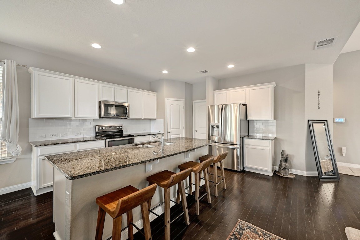 10104 Wading Pool Path Austin, TX 78748 - Photo 6 of 25 a kitchen with stainless steel appliances granite countertop a stove a sink a refrigerator and white cabinets with wooden floor