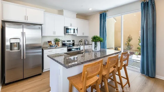 a kitchen with stainless steel appliances granite countertop a table chairs and a refrigerator