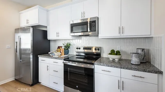 a kitchen with granite countertop white cabinets stainless steel appliances and sink